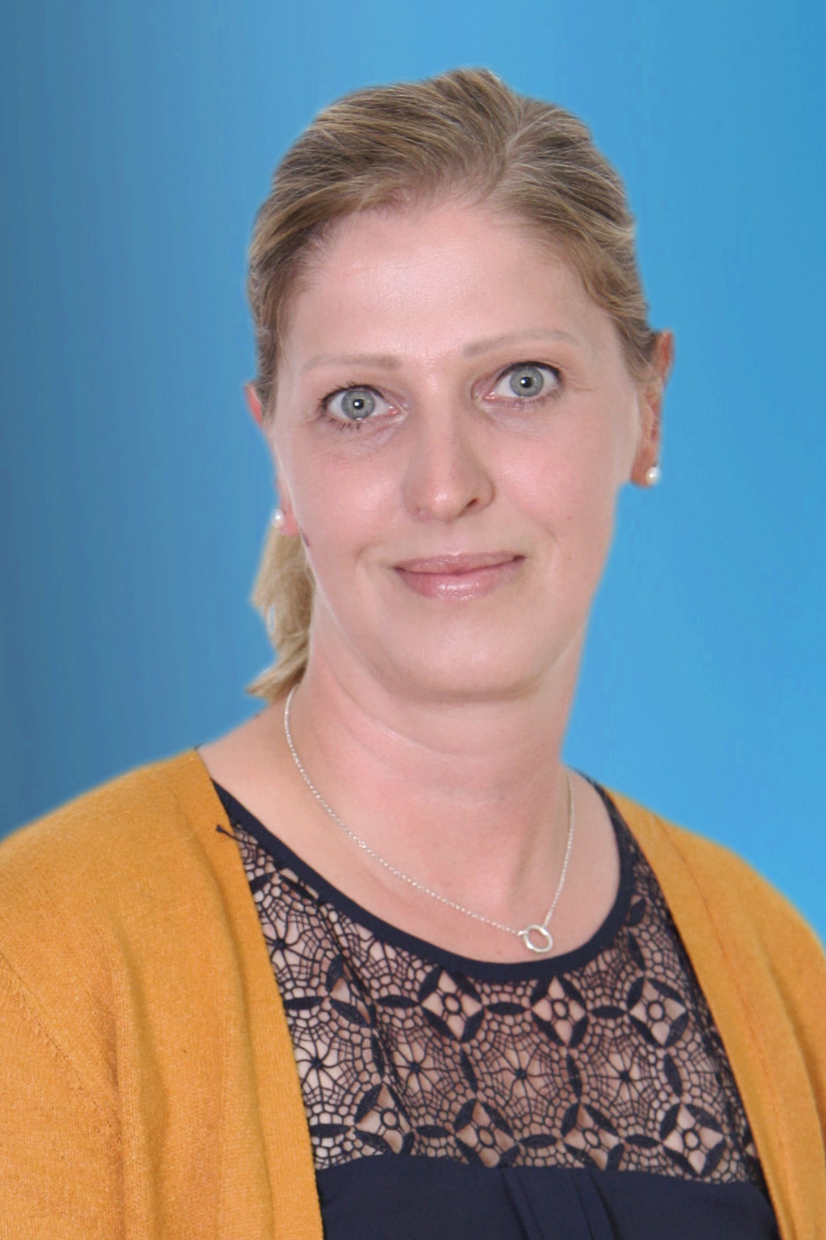 Mitarbeiterin von KARAWANE vor einem blauen Hintergrund