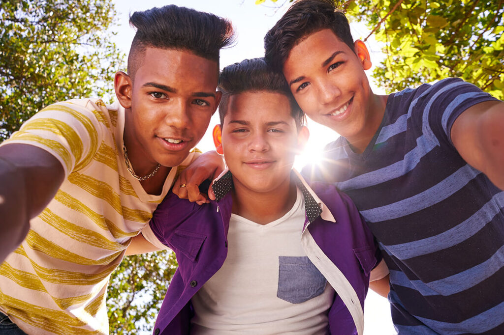 Drei Jungs mit unterschiedlichen Hautfarben stehen Arm in Arm in der Natur